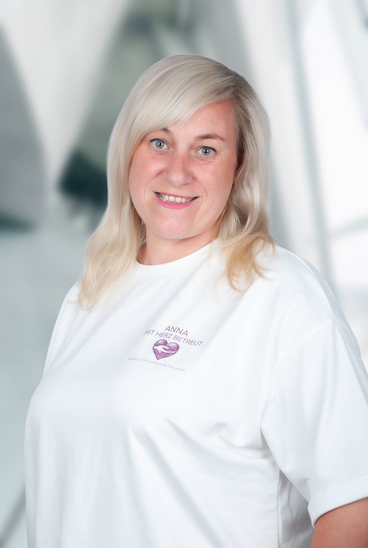 Anna Tödter lächelnd im weißen Shirt mit dem Logo von Anna mit Herz betreut